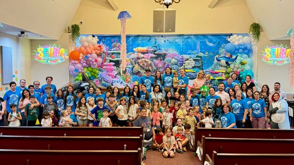 Kids and volunteers in matching shirts gathered in the sanctuary in front of an underwater-themed stage