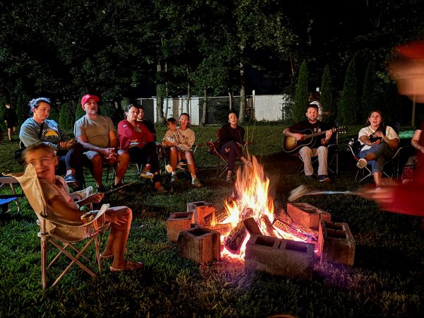 Families sitting in a circle around a campfire at night