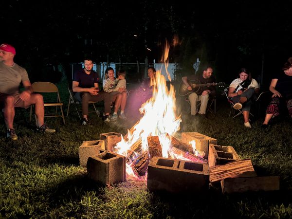 A bright campfire with friends sitting around it in the dark